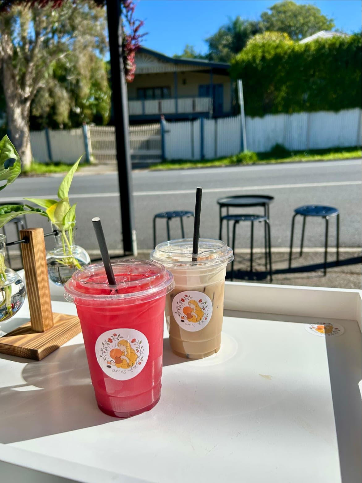 Two ames coffee cups on the footpath table with the residential street behind